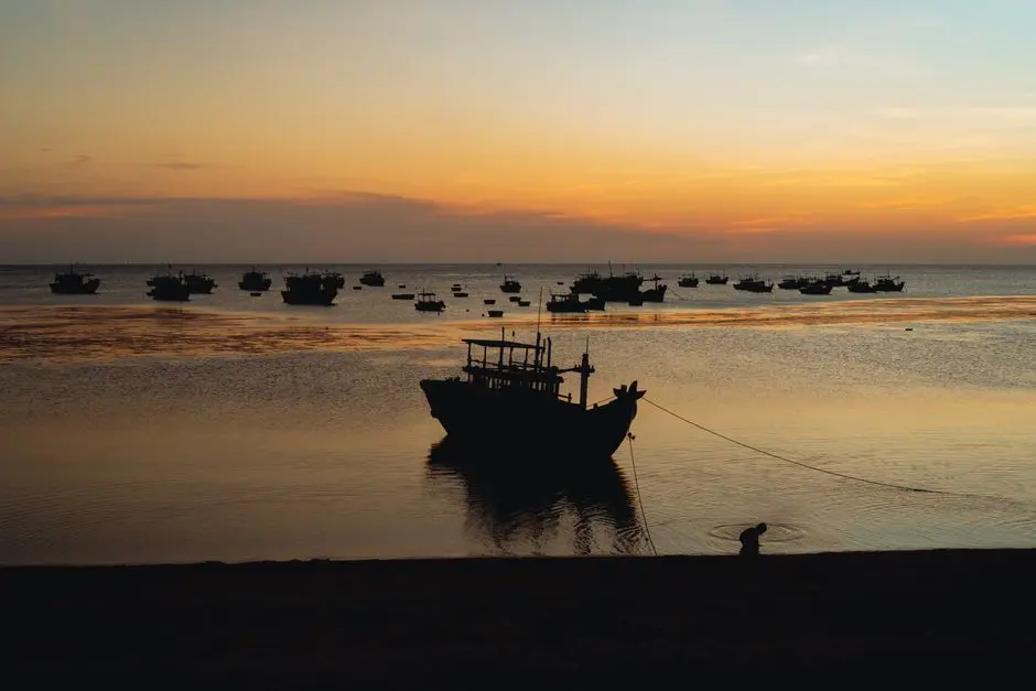 Suasana Pantai Tanjung Kalian saat senja dengan perahu nelayan di kejauhan